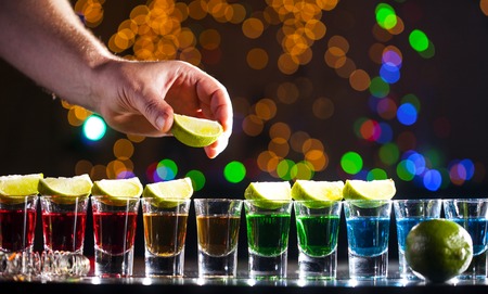 Alcoholic drink into small glasses on bar. Colorful cocktails at the bar. Colorful shots at the...