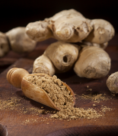 Ginger root and ginger powder in spoon on wooden backgroundの写真素材