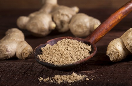 Ginger root and ginger powder in spoon on wooden backgroundの写真素材