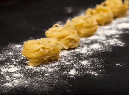 Italian traditional raw pasta on the black stone background. Closeup with copy spaceの写真素材