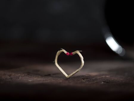 Two matchsticks made in the shape of a heart ob dark background. Love concept.の写真素材