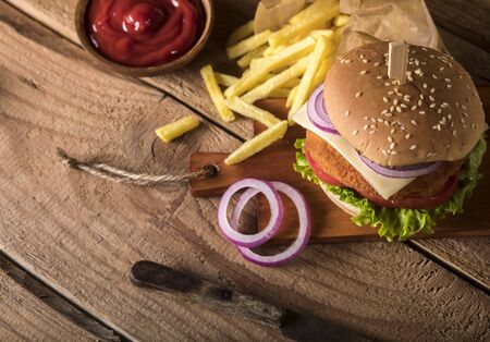 Fresh delicious burger with meatball, cheese, tomato, onion and lettuce on wooden table.の写真素材