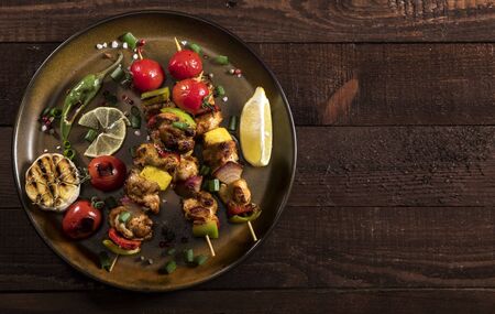 Grilled chicken skewers with spices and vegetables in a pan on a wooden background. Top view.の写真素材