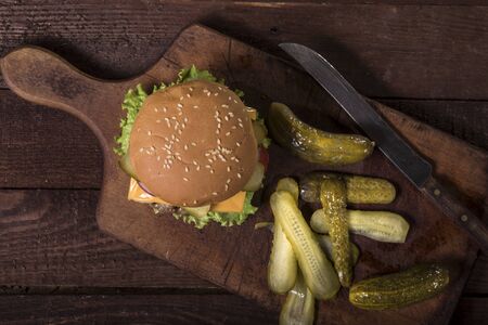 Preparation of fresh delicious burger with meatball, cheese, tomato, onion, lettuce, pickles on wooden table. Top view.の写真素材