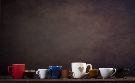 Collection of different cups on wooden table and dark brown background with copy spaceの写真素材