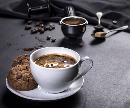 Coffee cup, cookies and utensils for coffee maker on black backgroundの写真素材
