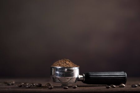 Strainer with coffee powder and coffee beans on wooden table and brown backgroundの写真素材