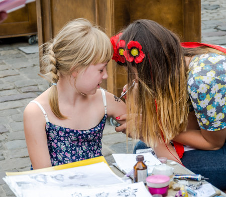 Lviv, Ukraine - August 2015: Tattoo artist doing temporary henna tattoo on the hand of the girlのeditorial素材