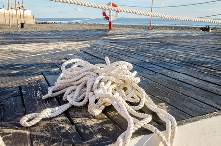 Sea white ship on a mooring rope is among the lifebuoys on the waterfront in Italyの写真素材