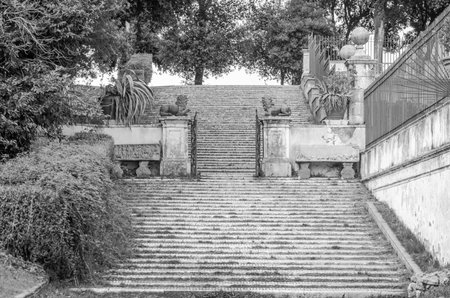 The steps and the road between the sculptures in the trees, bushes and grass in park at Villa Pamphili in Rome, capital of Italyのeditorial素材