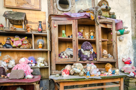 Collection of children abandoned old vintage retro plush and plastic toys and dolls standing on an old wooden furniture in the yard on the streetのeditorial素材
