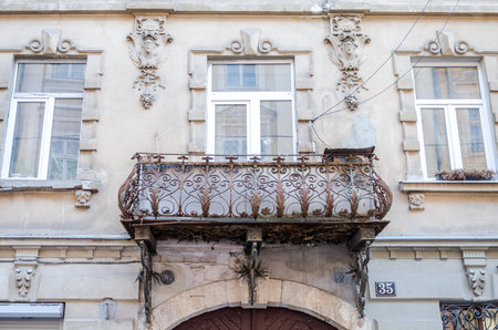 Old vintage retro classic wrought-iron balconies of metal with color patterns on an old brick building with windowsのeditorial素材