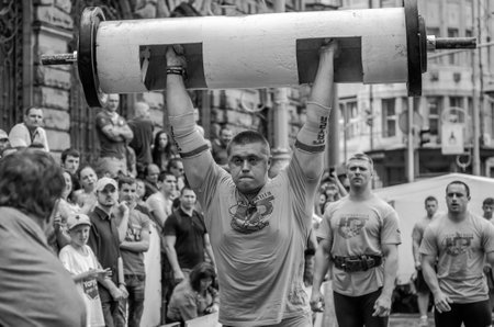 LVIV, UKRAINE - JUNE 2016: Strong athlete bodybuilder strongman inflated with a beautiful body to lift heavy barbell on the streetのeditorial素材