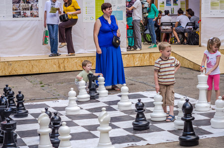 LVIV, UKRAINE - JUNE 2016: Young children, the future grandmasters play on a chess board chess exercising outdoors huge figuresのeditorial素材