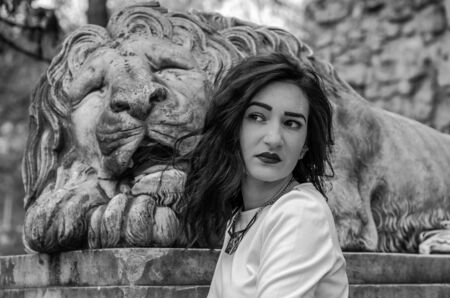 Young beautiful girl near the statue of a stone lion during a walk in the city of Lvivの写真素材