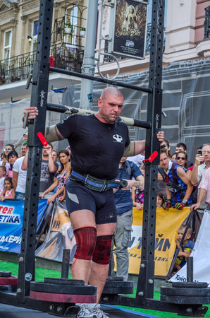 LVIV, UKRAINE - AUGUST 2017: Strong athlete bears a heavy huge rocker on the heroic games at Strongmen gameのeditorial素材