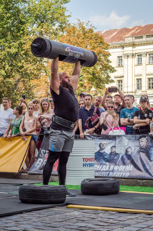 LVIV, UKRAINE - AUGUST 2017: A strong athlete picks up a huge heavy pack of barbell at Strongmen gamesのeditorial素材