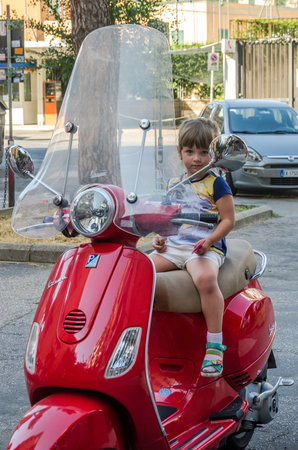 ROMA, ITALY - JULY 2017: A small beautiful tourist girl riding a Vespa motorcycle through the streets of ancient Romeのeditorial素材