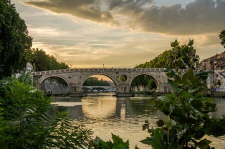 Bridge over the Tiber River at sunset on a summer evening in Rome, Italy