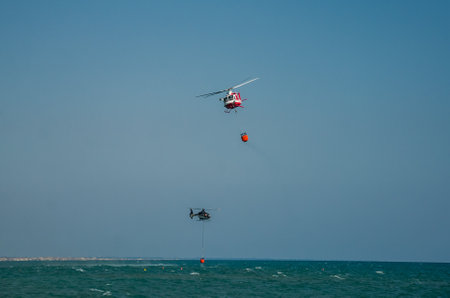ROMA, ITALY - JULY 2017: A fire helicopter is picking up the water in a basket for extinguishing a...