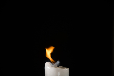 Burning candle with fading flame and smoke on a black backgroundの写真素材