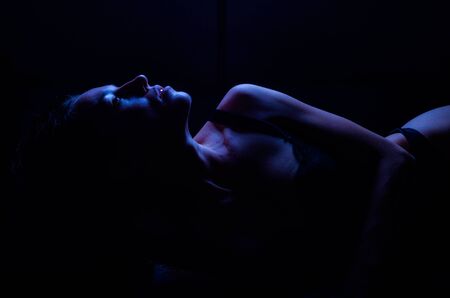 Young sexy girl in a beautiful erotic lace underwear lying isolated on a black backgroundの写真素材