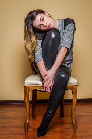 Young beautiful girl with long hair sits on a vintage classic wooden chair isolated on a light backgroundの写真素材