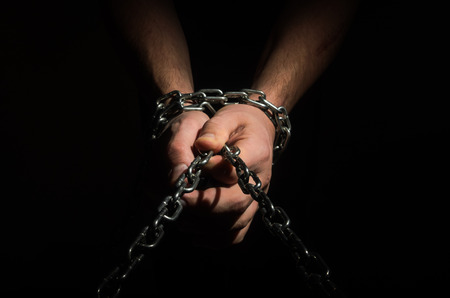 Hands are chained in chains isolated on black backgroundの写真素材