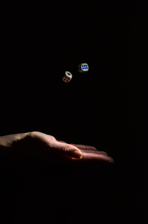 The hand throws dice to play a board game isolated on a black background