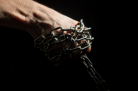 Hands are chained in chains isolated on black backgroundの写真素材