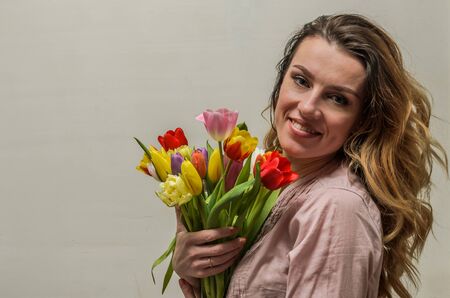 Young beautiful girl with a bouquet of flowers - multi-colored tulipsの写真素材