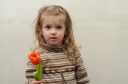 Happy baby girl rejoices and smiles with a bouquet of multi-colored tulips in handsの写真素材