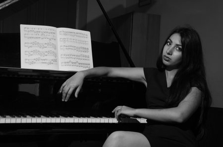 LVIV, UKRAINE - JUNE 2018: Young charming brunette girl playing the piano with notesのeditorial素材