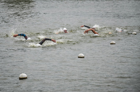 UKRAINE, LVIV - SEPTEMBER 2018: Athletes swimmers swim along the lake in wetsuits during the triathlon competitionのeditorial素材