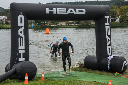 UKRAINE, LVIV - SEPTEMBER 2018: An athlete runs out of the water in a hydro-suit after a swim during a triathlon competitionのeditorial素材