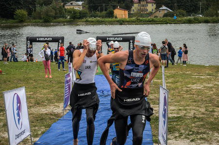 UKRAINE, LVIV - SEPTEMBER 2018: An athlete runs out of the water in a hydro-suit after a swim during a triathlon competitionのeditorial素材