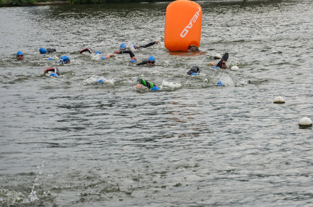 UKRAINE, LVIV - SEPTEMBER 2018: Athletes swimmers swim along the lake in wetsuits during the triathlon competitionのeditorial素材