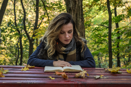 Young beautiful girl sitting in autumn parkの写真素材
