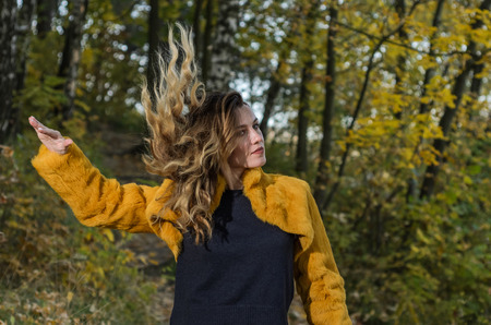 Young beautiful girl with long hair walks in the autumn forestの写真素材
