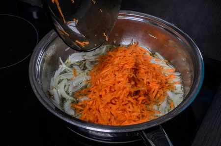 Onions and carrots are fried in a pan in sunflower oilの写真素材