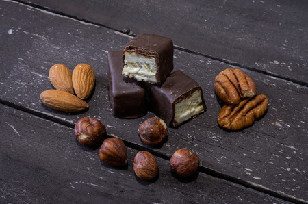 Chocolate candies and nuts on a wooden tableの写真素材