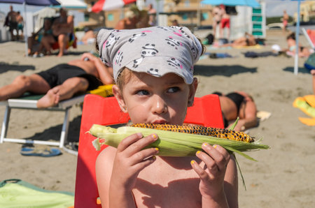 ROMA, ITALY - JULY 2019: Little kid girl eating fried popcorn on the beachのeditorial素材