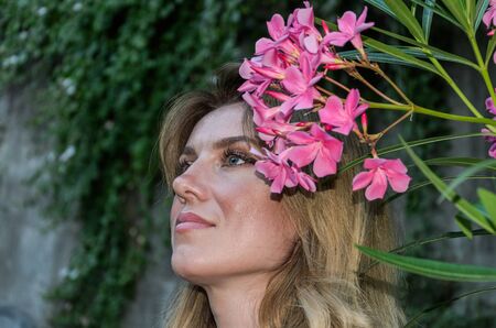 Young charming girl sniffs white flowers on a bush