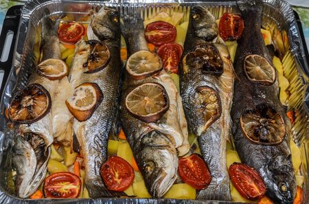 Roasted fish with vegetables and lemon in aluminum form