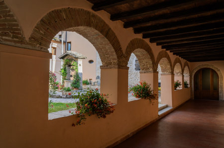 ROMA, ITALY - JULY 2019: Church courtyard with a corridor with arched windows with flowers and a well in the courtyardのeditorial素材