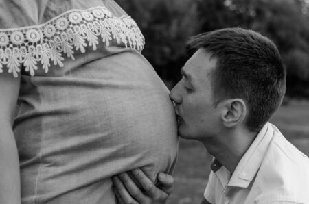 Loving husband kisses a pregnant wife in the stomach, happy familyの写真素材