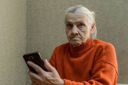 Elderly woman writes a message in a smartphoneの写真素材