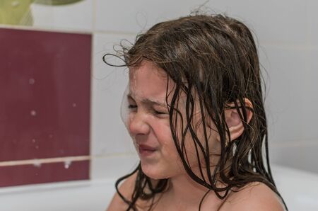 Little charming baby girl bathes in a bath with foam
