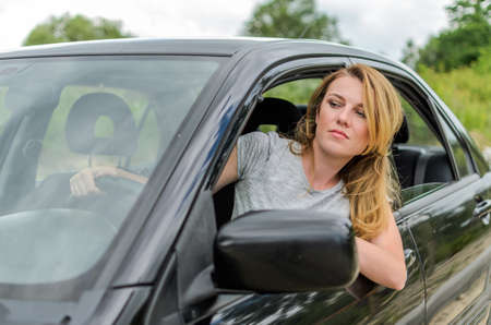 Young charming girl driving a black car