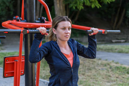 Young women doing sports on outdoor exercise machine in the stadium